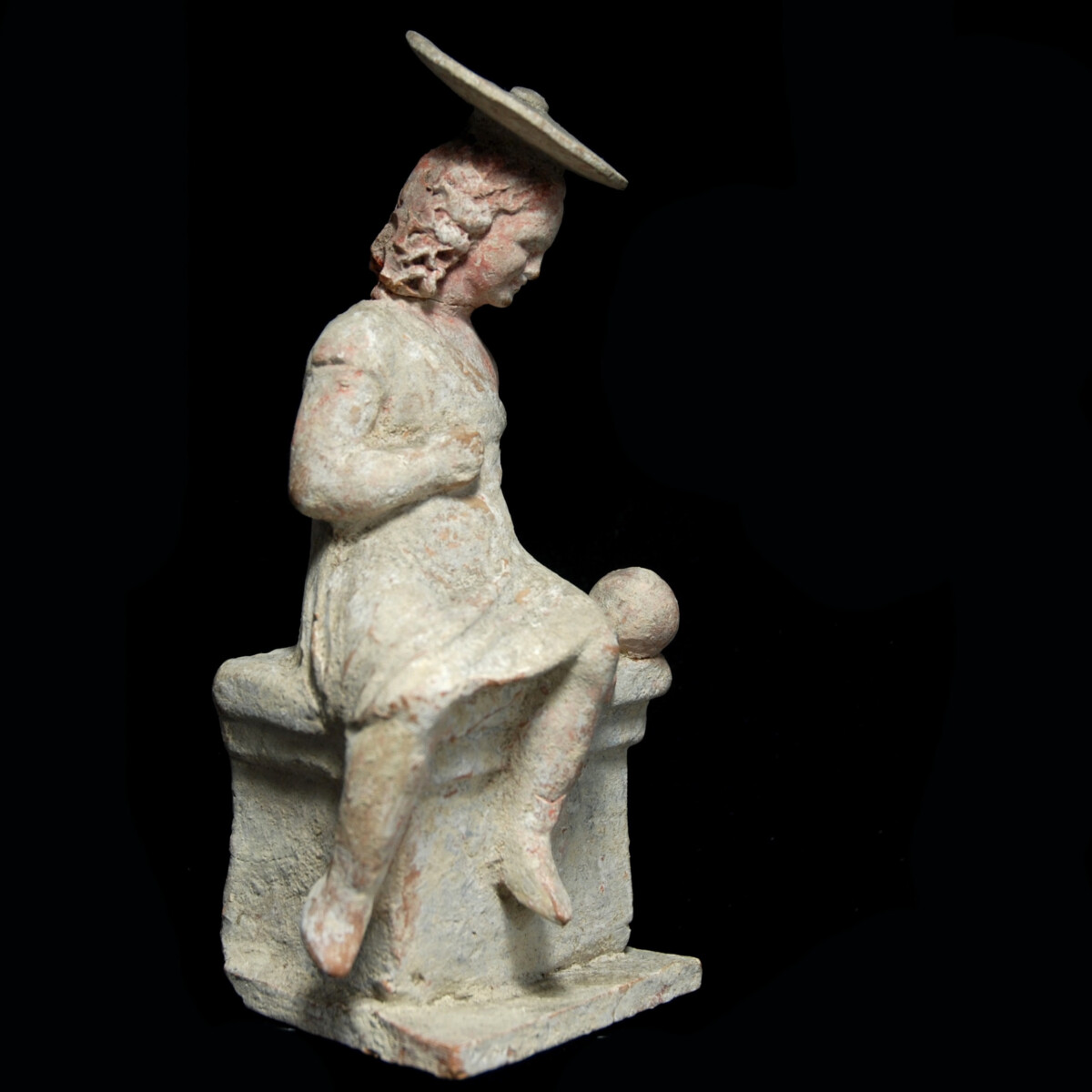 Hellenistic Tanagra statuette of a girl with sun hat and ball half right